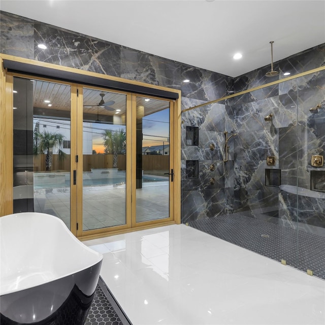 bathroom featuring ceiling fan, a bathtub, tile walls, and tile patterned flooring