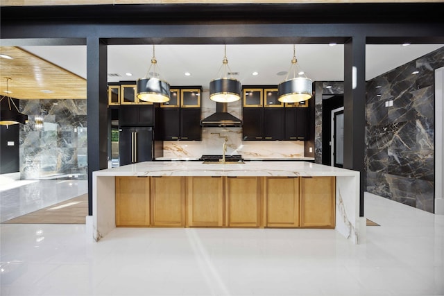 kitchen with light stone counters, backsplash, pendant lighting, a kitchen island with sink, and high end fridge