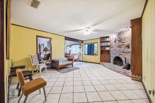 living room featuring ceiling fan, a fireplace, light tile patterned floors, and a textured ceiling