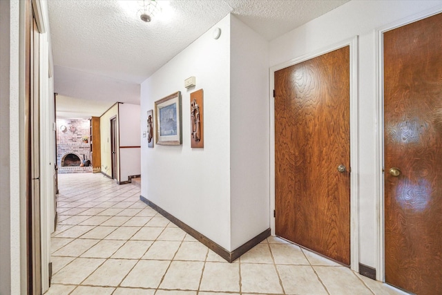 hall featuring light tile patterned floors and a textured ceiling