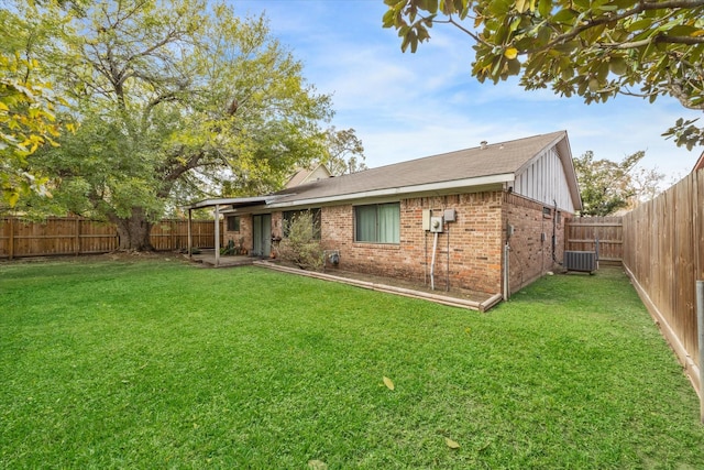 rear view of property featuring a lawn and cooling unit