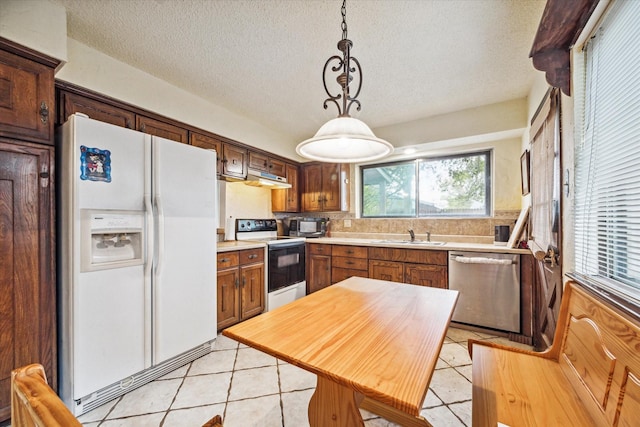 kitchen featuring pendant lighting, white appliances, backsplash, a textured ceiling, and light tile patterned flooring