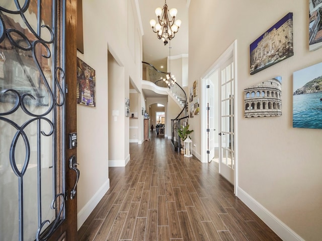 entryway with a chandelier, french doors, dark wood-type flooring, and a high ceiling