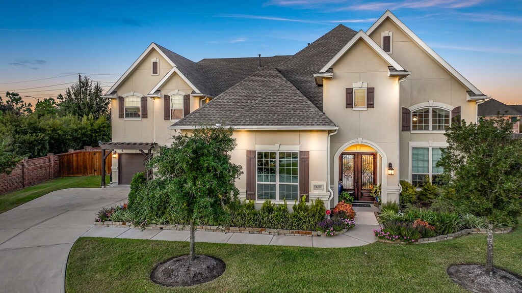 view of front of property featuring a garage, a yard, and french doors