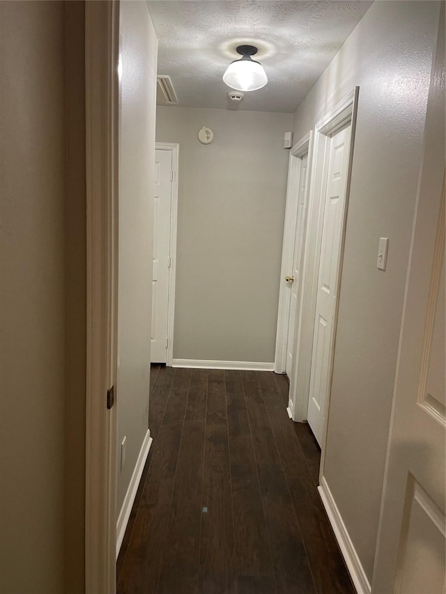 hall featuring dark wood-type flooring and a textured ceiling