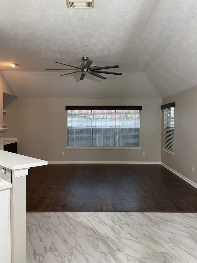 unfurnished living room with ceiling fan, lofted ceiling, and a textured ceiling