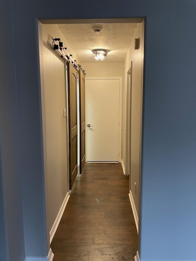 hallway with dark wood-type flooring and a textured ceiling