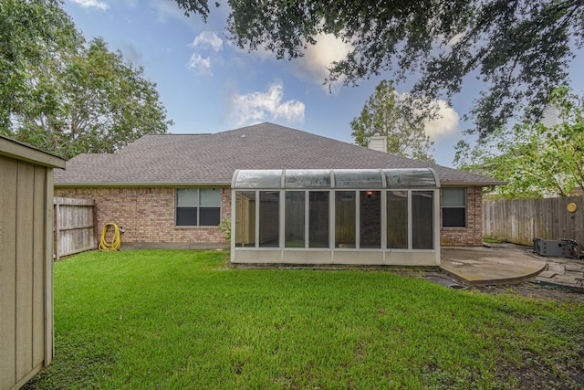 rear view of property with a sunroom, a patio area, and a lawn