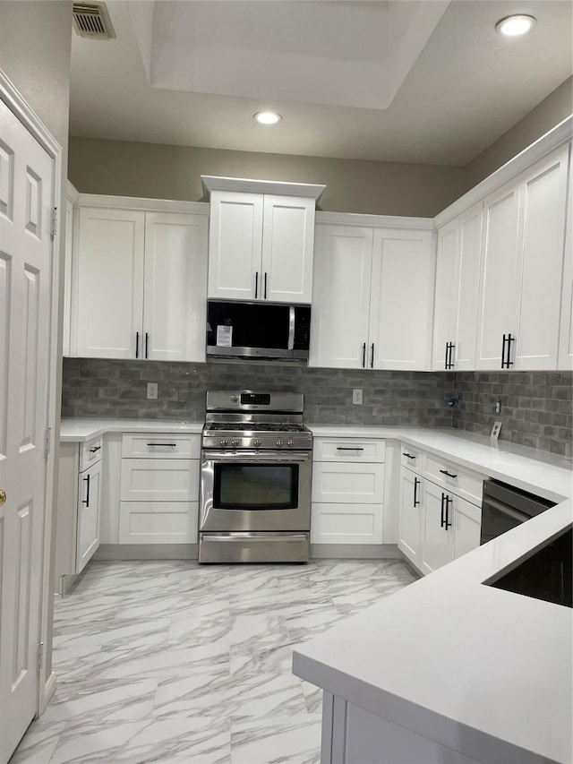 kitchen featuring tasteful backsplash, white cabinetry, and stainless steel appliances