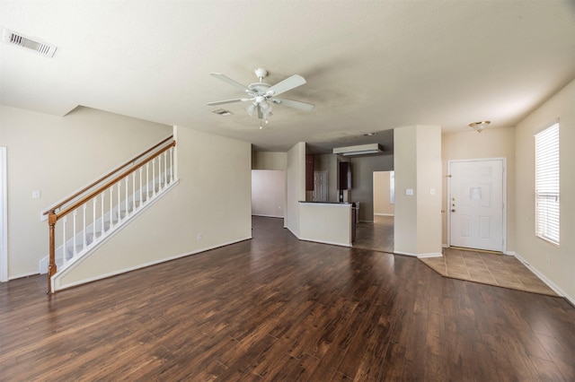 unfurnished living room featuring ceiling fan, dark wood-type flooring, and a wall mounted air conditioner