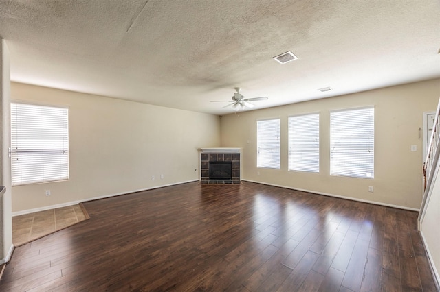 unfurnished living room with dark hardwood / wood-style flooring, a textured ceiling, and a tile fireplace