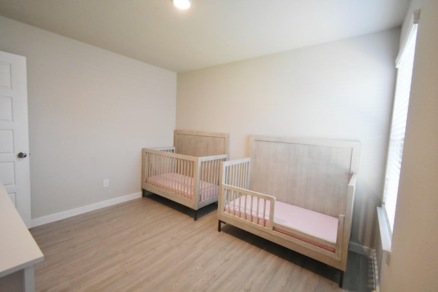 bedroom featuring multiple windows, hardwood / wood-style floors, and a nursery area