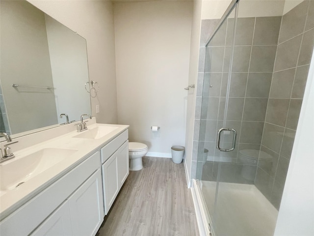 bathroom with hardwood / wood-style floors, vanity, a shower with shower door, and toilet