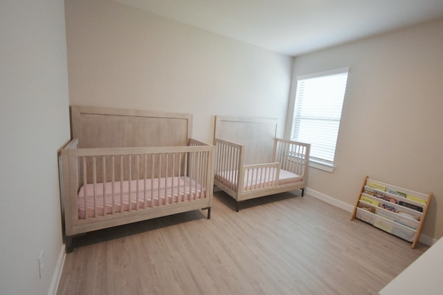 bedroom featuring light hardwood / wood-style floors and a crib