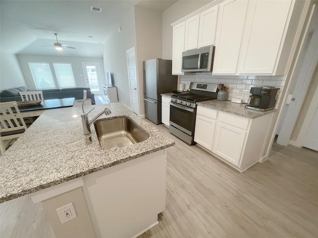 kitchen with white cabinetry, sink, ceiling fan, stainless steel appliances, and light stone counters