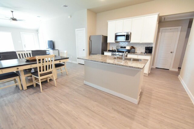 kitchen featuring white cabinets, sink, decorative backsplash, appliances with stainless steel finishes, and light stone counters