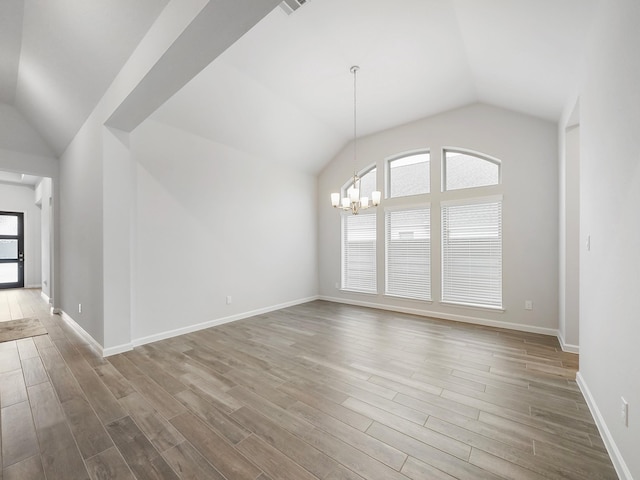 unfurnished room with lofted ceiling, wood-type flooring, and an inviting chandelier