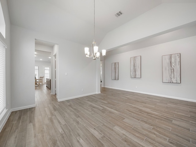 interior space featuring hardwood / wood-style flooring, a notable chandelier, and vaulted ceiling