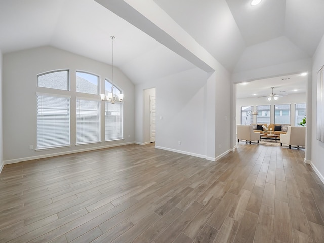 unfurnished living room with a healthy amount of sunlight, ceiling fan with notable chandelier, and light wood-type flooring