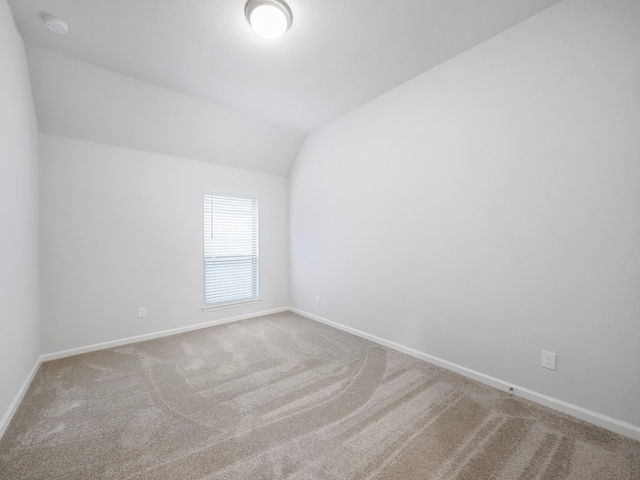 carpeted spare room with lofted ceiling