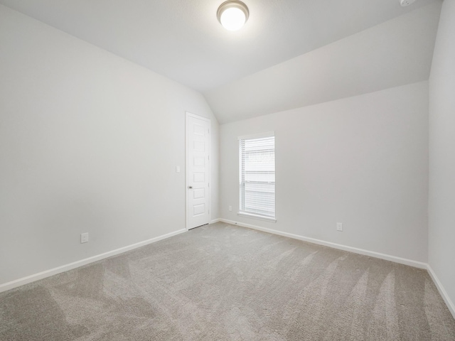 carpeted empty room with lofted ceiling