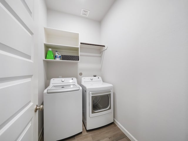 laundry room featuring washing machine and dryer and light hardwood / wood-style floors