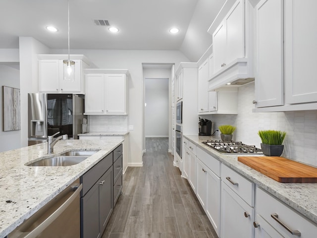 kitchen with appliances with stainless steel finishes, sink, decorative light fixtures, light hardwood / wood-style flooring, and white cabinetry