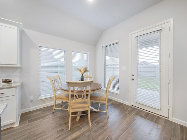 dining area featuring dark wood-type flooring and vaulted ceiling