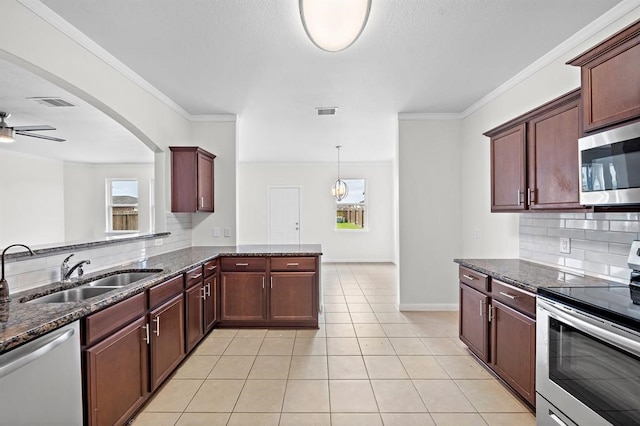 kitchen featuring kitchen peninsula, backsplash, stainless steel appliances, sink, and dark stone countertops