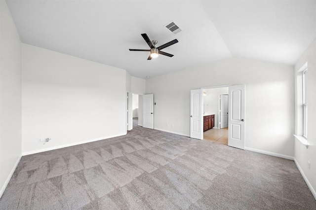 unfurnished bedroom featuring ceiling fan, light carpet, connected bathroom, and vaulted ceiling