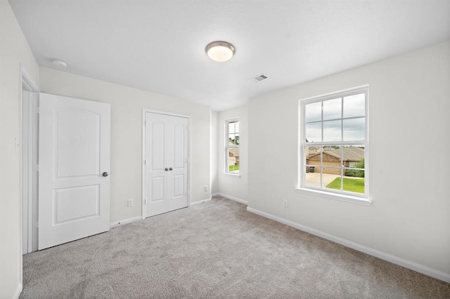 unfurnished bedroom with light colored carpet and a closet