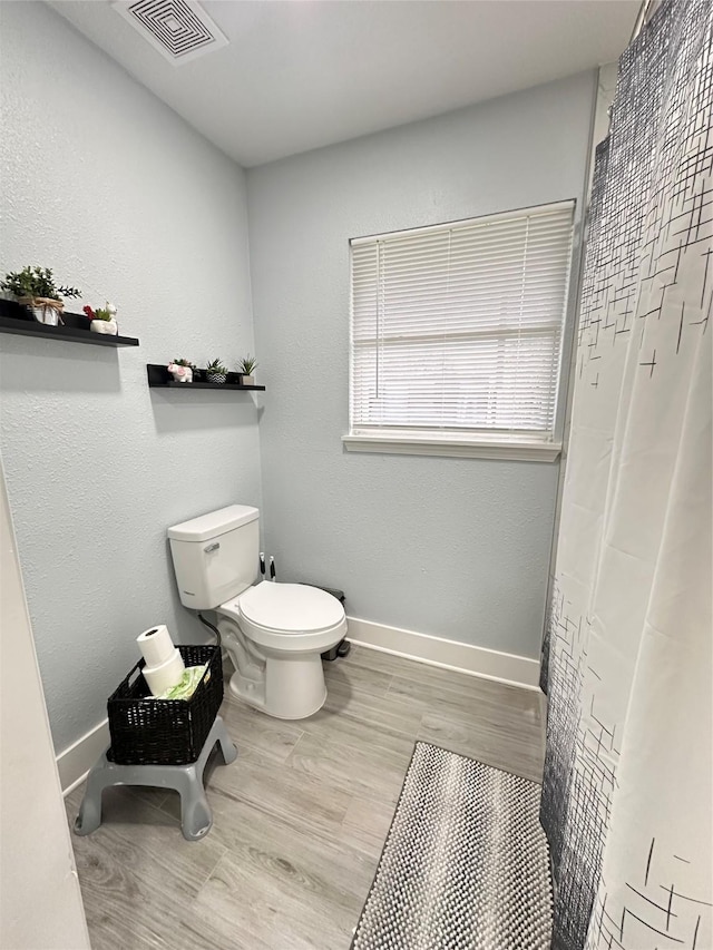 bathroom with a shower with shower curtain, wood-type flooring, and toilet