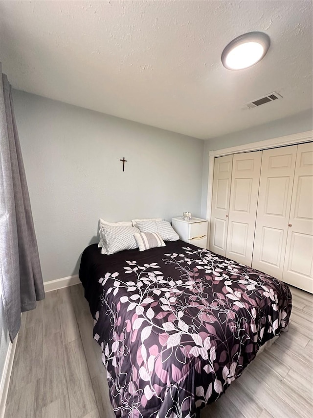 bedroom with a textured ceiling, hardwood / wood-style flooring, and a closet