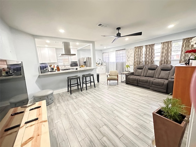 living room with plenty of natural light, ceiling fan, and light hardwood / wood-style flooring