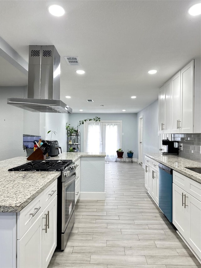 kitchen with light stone counters, ventilation hood, stainless steel appliances, light hardwood / wood-style flooring, and white cabinets