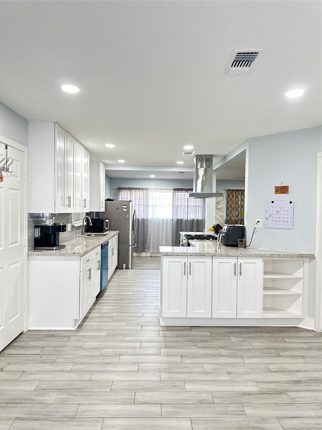 kitchen with kitchen peninsula, light stone counters, white cabinets, and appliances with stainless steel finishes