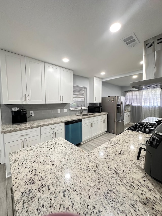 kitchen featuring wall chimney range hood, appliances with stainless steel finishes, plenty of natural light, light hardwood / wood-style floors, and white cabinetry