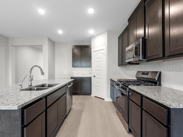 kitchen featuring light hardwood / wood-style flooring, appliances with stainless steel finishes, sink, and a kitchen island with sink