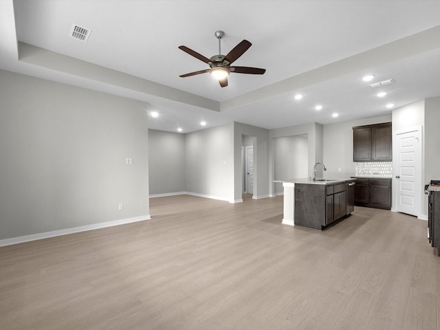 kitchen featuring light hardwood / wood-style flooring, an island with sink, dark brown cabinetry, decorative backsplash, and sink