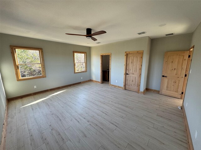 unfurnished bedroom with light wood-type flooring, ceiling fan, and a spacious closet