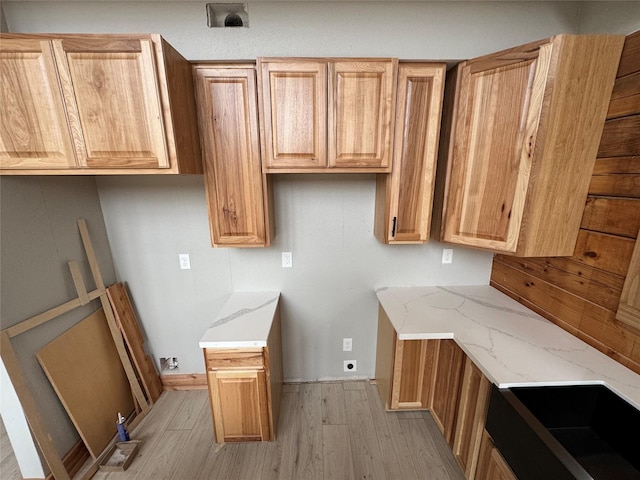 kitchen featuring light stone countertops, sink, and light hardwood / wood-style flooring