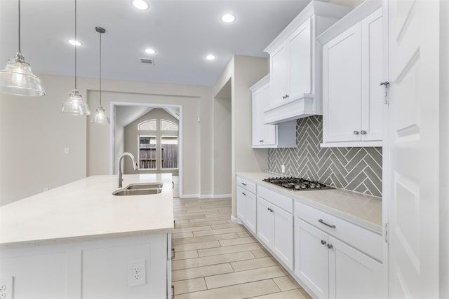 kitchen featuring decorative light fixtures, white cabinetry, stainless steel gas stovetop, and sink