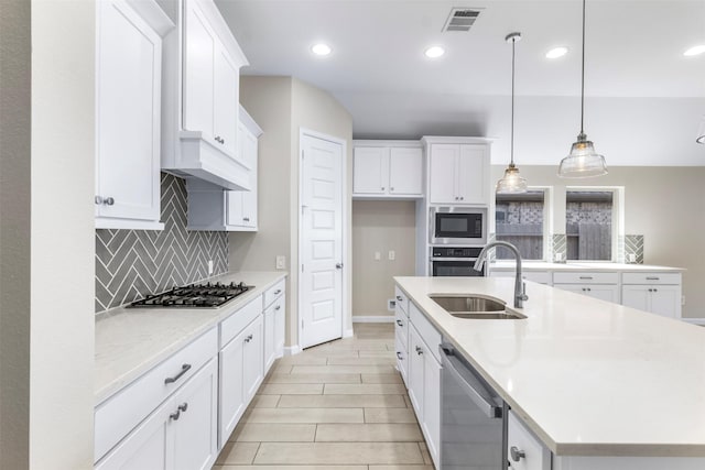 kitchen featuring stainless steel appliances, a kitchen island with sink, sink, pendant lighting, and white cabinets