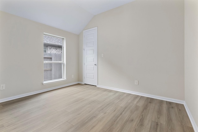 empty room with light hardwood / wood-style floors and lofted ceiling