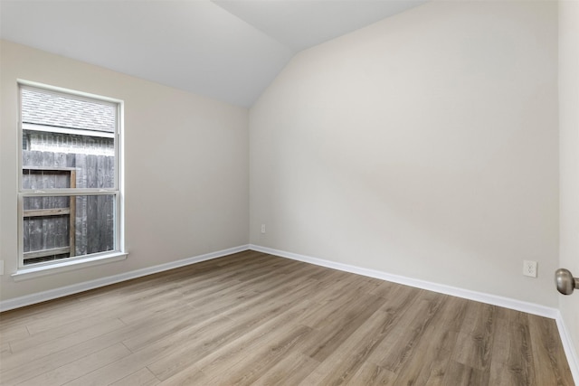 empty room with light hardwood / wood-style flooring and vaulted ceiling