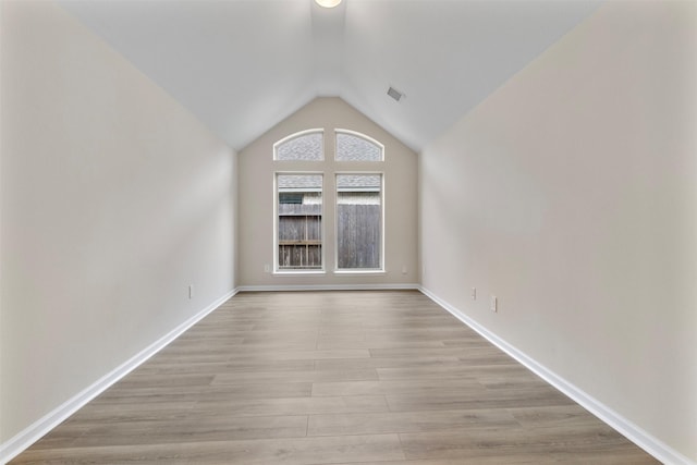 empty room with vaulted ceiling and light hardwood / wood-style flooring