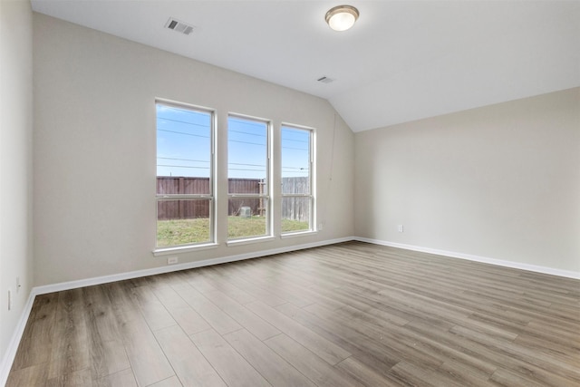 spare room with light hardwood / wood-style floors and vaulted ceiling