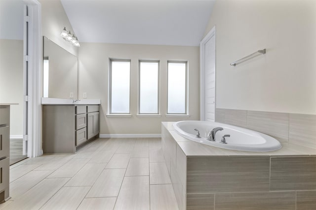 bathroom with vanity, tiled bath, and lofted ceiling