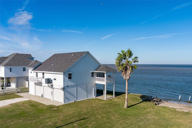 back of house featuring a yard, a balcony, a water view, and a garage