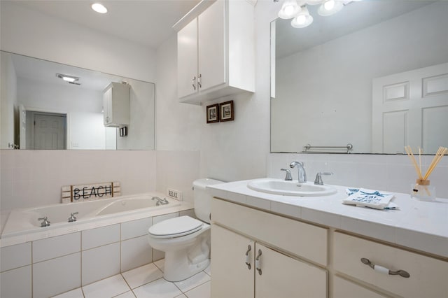 bathroom featuring tile patterned floors, vanity, a relaxing tiled tub, and toilet